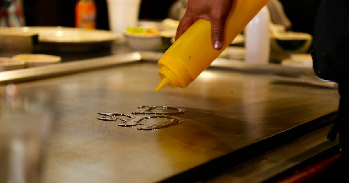 person putting oil on a griddle