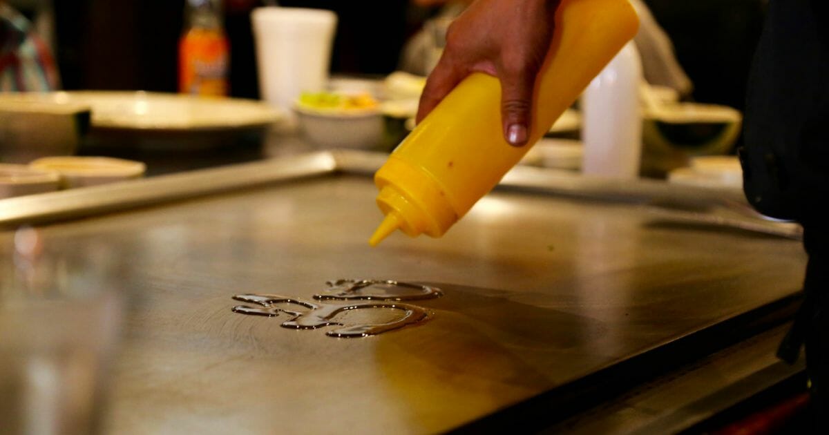 person putting oil on a griddle